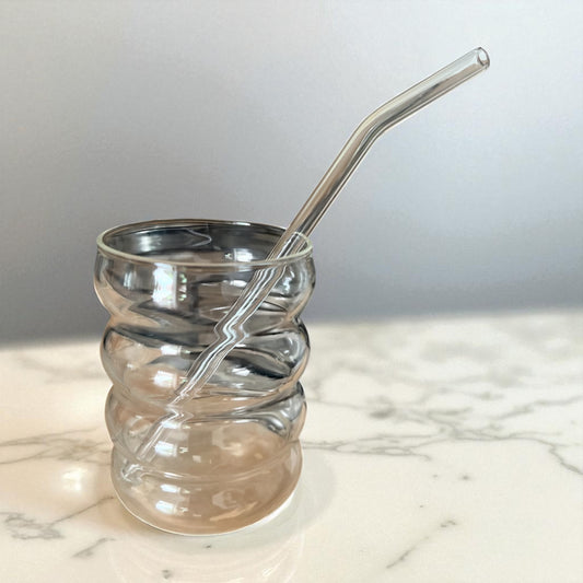 Présentation d'un verre à matcha design en verre, effet ondulé. Le verre est vide, et contient une paille en verre.